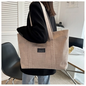 Detail of canvas tote bag showing natural fabric texture and fashion label on front