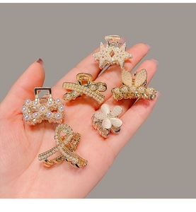 Miniature gold alloy hair claws with pearls and rhinestones shown for size reference