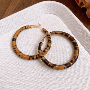 Macro shot of large hoop earrings featuring brown leopard print leather and gold clasp