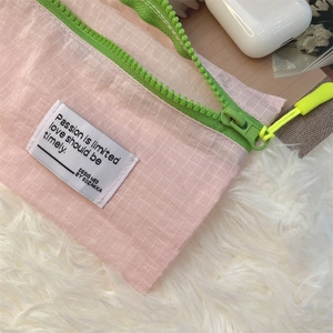 Pink mesh luggage organizer detail with green zipper and woven label decoration
