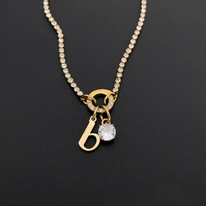 Close-up of gold titanium steel necklace featuring letter 'b' and round CZ pendant