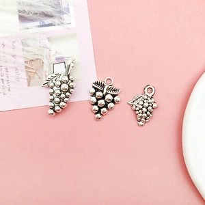 Three silver grape cluster charms with leaves for DIY jewelry making on pink background