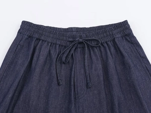Detail of deep blue denim trousers showing elastic waistband with matching drawstring