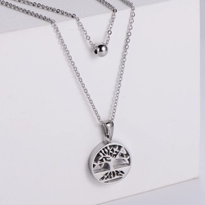 Double-layered silver steel necklace with tree of life and round bead pendants on white blocks