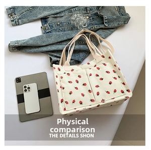 Detail showing off-white corduroy tote bag with red strawberry print and front pockets