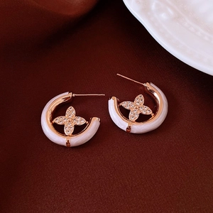 Detailed view of C-shaped rose gold earrings with white enamel and zircon flower