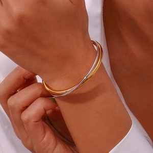 Close-up of a double-layer crisscross bangle in gold and silver finish on a model