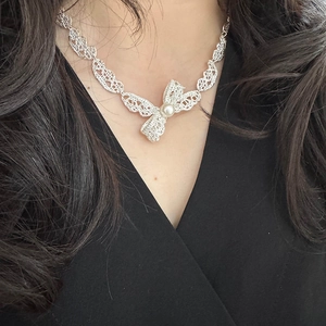 Collier pendentif nœud en dentelle avec perle sur mannequin en haut noir col en V