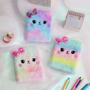 Detailed view of plush cat journals with tie-dye faux fur and sequin bow embellishments