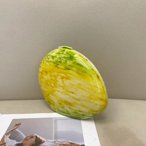 Detail of yellow and green marble pattern on an oval-shaped ceramic clutch bag
