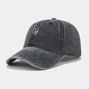 Close-up of heart embroidery on washed dark gray cotton baseball cap with stitch detail