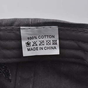 Detail view of cotton baseball cap washing label showing 100% cotton fabric and care icons