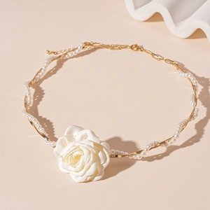 Elegant gold necklace with white fabric flower and pearls for a resort style look