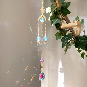 Detailed sun catcher with blue crystals and gold stars reflecting rainbow spots on a wall