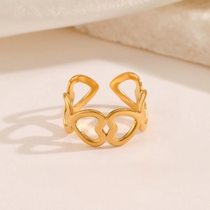 Gold minimalist open ring with hollow heart pattern on warm stone background