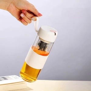 Detail of hand holding portable glass tea infuser bottle with protective sleeve and carry strap