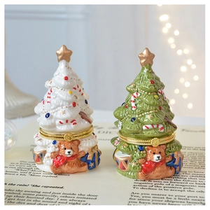 Detail of handcrafted ceramic Christmas tree jewelry boxes with gold hinges on vintage book pages