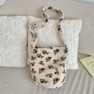 Close-up of fuzzy fleece shoulder bag with floral patterns on a cozy white pillow