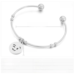 Macro detail of stainless steel cuff bracelet featuring a winking smiley face pendant