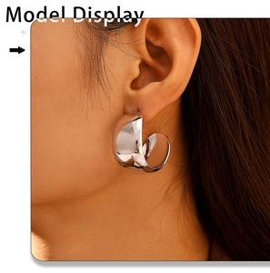 Close-up of thick silver hollow C-shaped hoop earrings with a polished mirror finish