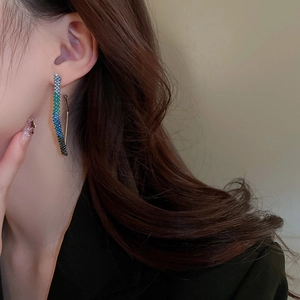 Close-up of elegant gradient blue rhinestone twisted earrings on a female model