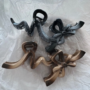 Macro detail of elegant gradient bow hair claws and wavy line hair clips in brown and grey