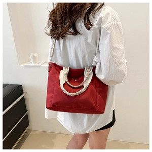 Red nylon tote bag with ethnic pattern straps and detachable shoulder strap on model