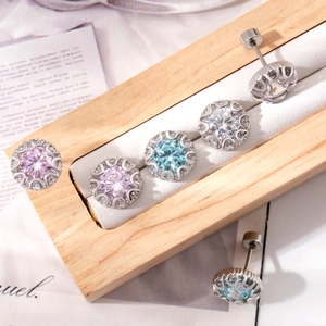 Sparkling zircon earrings in pink and blue colors on a wooden display stand