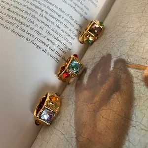 Vintage gold rings with colorful square gemstones and irregular molten texture on art book