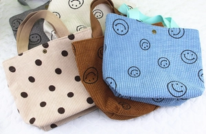Détail de cinq sacs cabas en velours côtelé avec smileys et boutons-pression en bronze