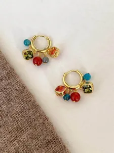 Detail of bohemian hoop earrings with colorful zircon beads and tassel charms in gold