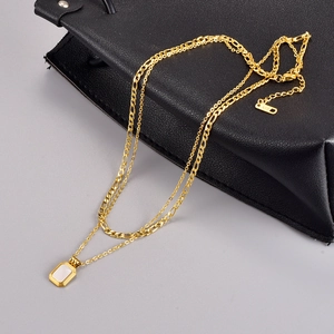 Double-layered golden necklace with rectangular white pendant and Figaro chain links