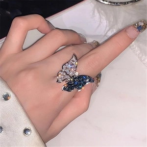 Macro shot of micro-paved blue and white zircon butterfly ring on a marble surface