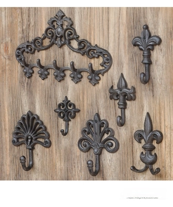 Detail of vintage cast iron wall hooks with fleur-de-lis designs on a rustic wood surface