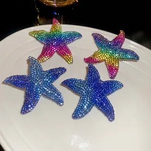 Starfish pendant earrings with colorful crystals in a ceramic dish, elegant summer style