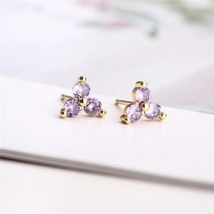 Macro shot of gold stud earrings featuring small purple zircon stones in a triangle shape