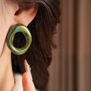 Close-up of a model wearing green vintage glass floral hoop earrings with a glossy finish