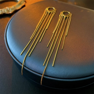 Detail of long gold tassel earrings hanging over a blue leather jewelry box