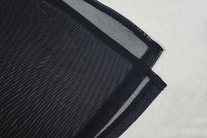Close-up of semi-transparent black mesh fabric with professional double-stitched hem