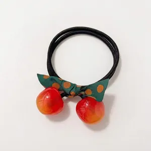Cute cherry and bow hair tie featuring red resin charms and green polka dot ribbon