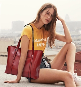 Detail of red faux leather tote bag with metallic buckles on a model in urban setting