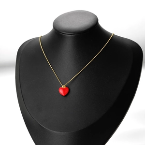 Golden bead chain necklace featuring a vibrant red enamel heart pendant on a model
