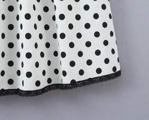 Close-up of elegant black polka dot fabric with delicate black lace trim at the hemline