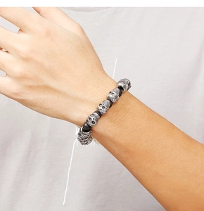 Macro detail of men's skull beaded bracelet with black lava stone and retro silver accents