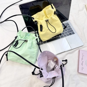 Dettaglio di mini borse a tracolla con coulisse in giallo, verde e viola su laptop