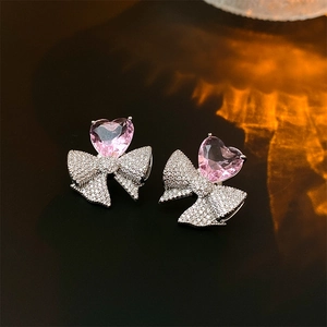 Gros plan sur les boucles d'oreilles cœur rose en zircon avec détail de nœud pavé