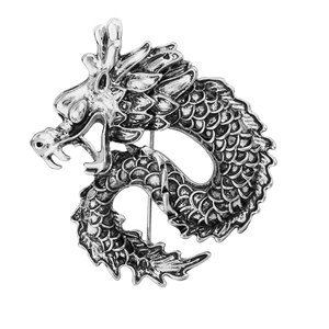 Close-up of vintage silver dragon brooch showing intricate scales and metallic texture