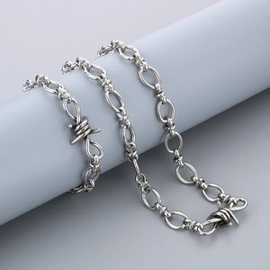 Detailed close-up of a silver punk thorn chain wrapped on a minimalist gray cylinder