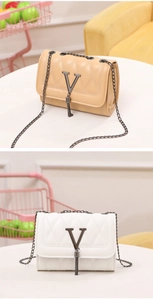 Detail of quilted leather crossbody bag with V-shaped metal logo and fringe tassel