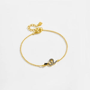 Detailed view of a gold snake pendant bracelet with sparkling zircons and a black stone head
